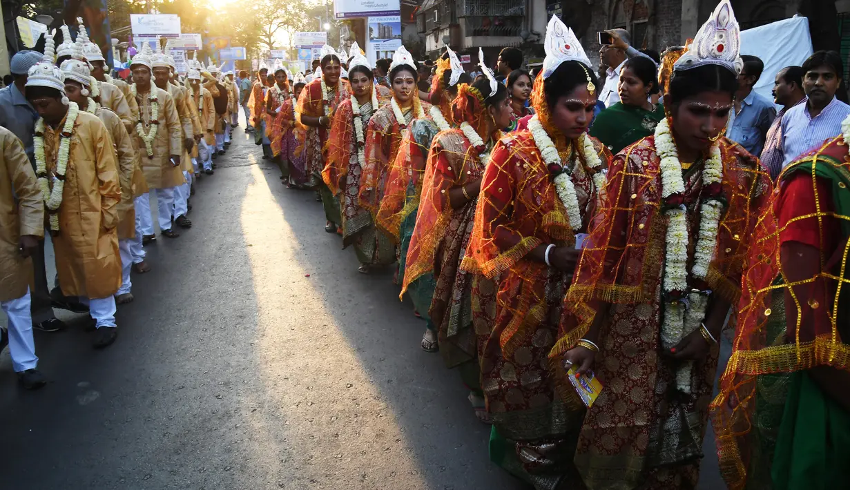 Iring-iringan calon pasangan pengantin di India saat mengikuti upacara pernikahan massal di Kolkata (14/2). Lebih dari 160 pasangan yang mengalami kesulitan ekonomi mengikuti acara nikah massal tersebut. (AFP Photo/Dibyangshu Sarkar)