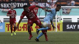 Bek Persija Jakarta, Tony Sucipto, berebut bola dengan striker Persela Lamongan, Delfin Rumbino, pada laga Shopee Liga 1 di Stadion Wibawa Mukti, Bekasi, Jumat (15/11). Persija menang 4-3 atas Persela. (Bola.com/Yoppy Renato)