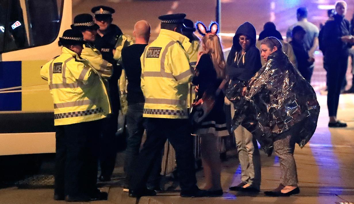 Personel darurat berbicara kepada warga di luar Manchester Arena, Inggris, usai ledakan di dalam tempat konser penyanyi Ariana Grande, Senin (22/5). Belum diketahui penyebab ledakan maupun pelaku dalam serangan tersebut. (Peter Byrne/PA via AP)