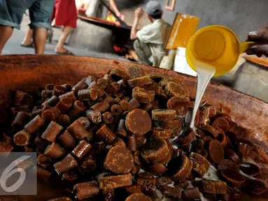 Pekerja menuangkan santan di atas gula aren di kawasan Pasar Minggu, Jakarta, Kamis (23/6). Produksi dodol Betawi mengalami peningkatan tajam seiring permintaan jelang Lebaran. (Liputan6.com/Gempur M Surya)