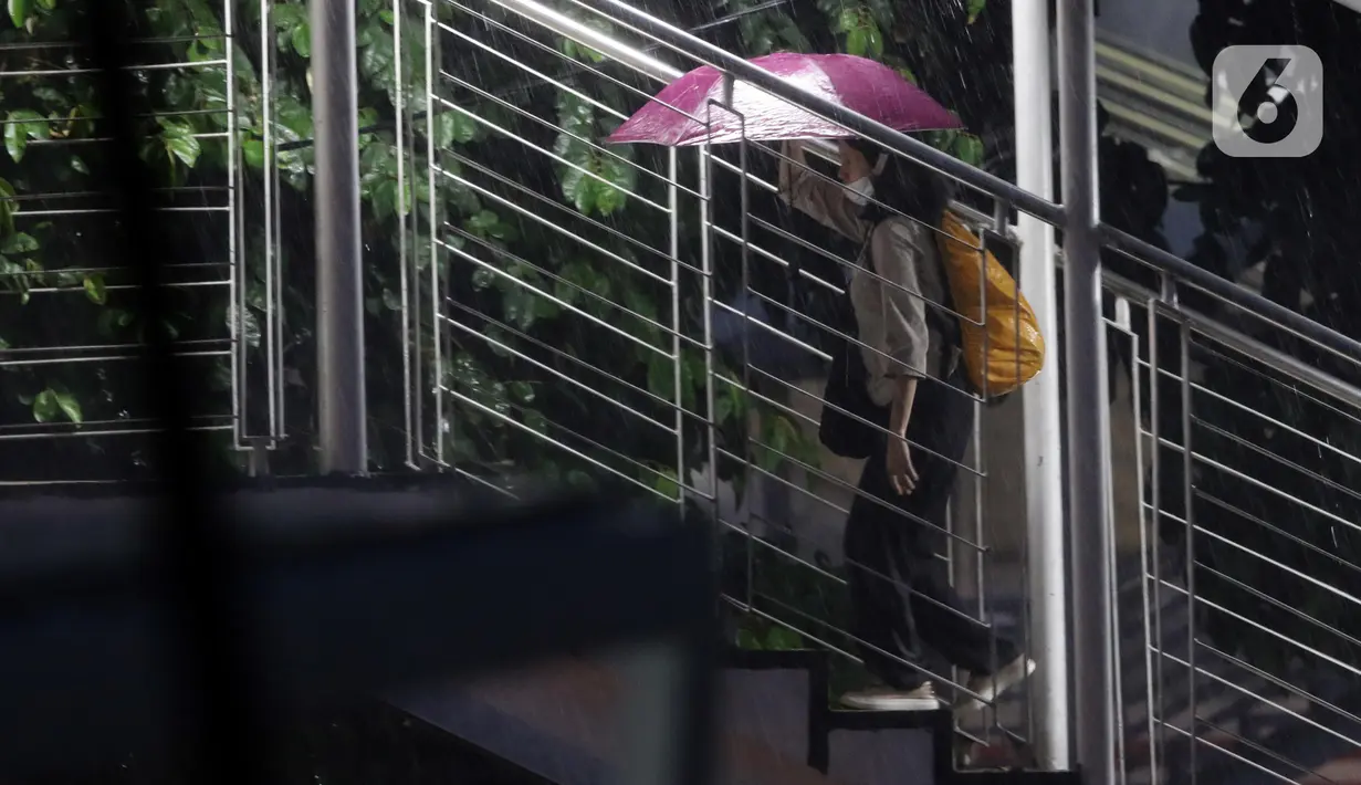Warga menggunakan payung saat melintas di Jembatan Penyebrangan Orang, kawasan Kuningan, Jakarta, Selasa (8/11/2022). Badan Meteorologi Klimatologi dan Geofisika (BMKG) memprakirakan puncak musim hujan di sebagian wilayah di Indonesia terjadi di bulan Desember 2022 hingga Januari 2023. (Liputan6.com/Helmi Fithriansyah)