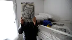 Farhad Nouri berfoto dengan lukisan Kanselir Jerman Angela Merkel yang dibuatnya, di kamarnya di dekat Belgrade, Serbia, 13 Maret 2017. Bocah Afganistan berusia 10 tahun ini dikenal dengan julukan Little Picasso karena bakat seninya. (AP/Darko Vojinovic)
