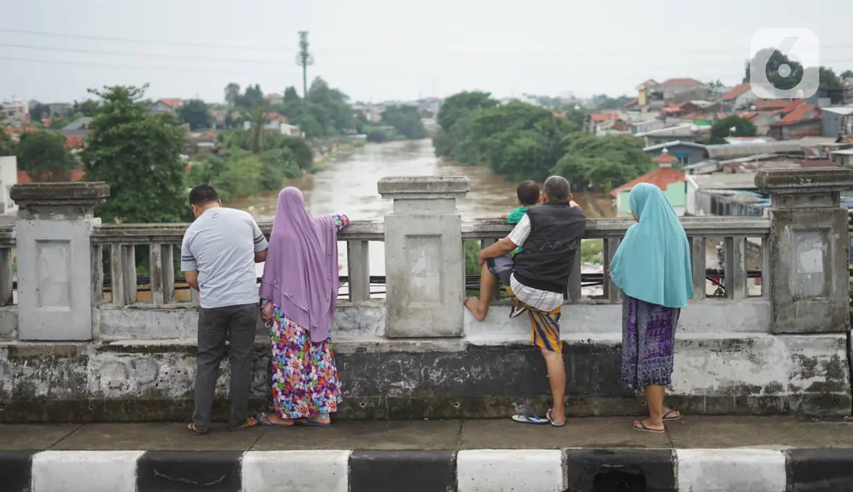 Sejumlah warga mengamati banjir yang menggenangi kawasan Rawajati dari atas flyover di Jakarta Timur, Rabu (1/1/2020). Banjir yang berasal dari luapan Sungai Ciliwung itu menjadi daya tarik tersendiri bagi sebagian pemotor yang melintasi di flyover tersebut. (Liputan6.com/Immanuel Antonius)