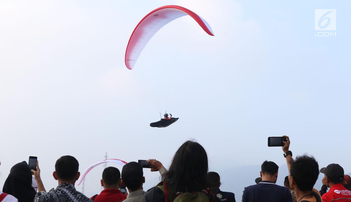 Salah satu atlet paralayang nomor cross country unjuk kebolehan saat latihan di kawasan Puncak, Cianjur, Jawa Barat, Kamis (26/7). Selain meninjau kesiapan venue, Menpora juga melihat latihan atlet paralayang Indonesia. (Liputan6.com/Helmi Fithriansyah)