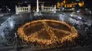 Orang-orang membuat tanda perdamaian dengan lampu saat demonstrasi untuk Ukraina yang diselenggarakan oleh Greenpeace di Heroes Square, Budapest, Hungaria, 9 Maret 2022. Invasi Rusia ke Ukraina telah memicu migrasi massal terbesar di Eropa dalam beberapa dekade. (AP Photo/Anna Szilagyi)
