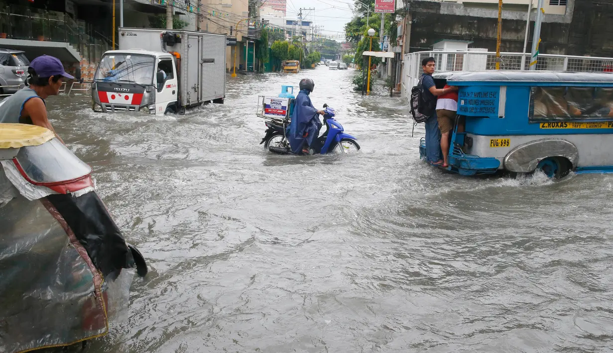 Warga berkendara ke tempat kerja meski banjir melanda Metropolitan Manila, Filipina, Jumat (20/7). Selain bagian Metropolitan Manila, banjir juga terjadi di provinsi lain. (AP Photo/Bullit Marquez)