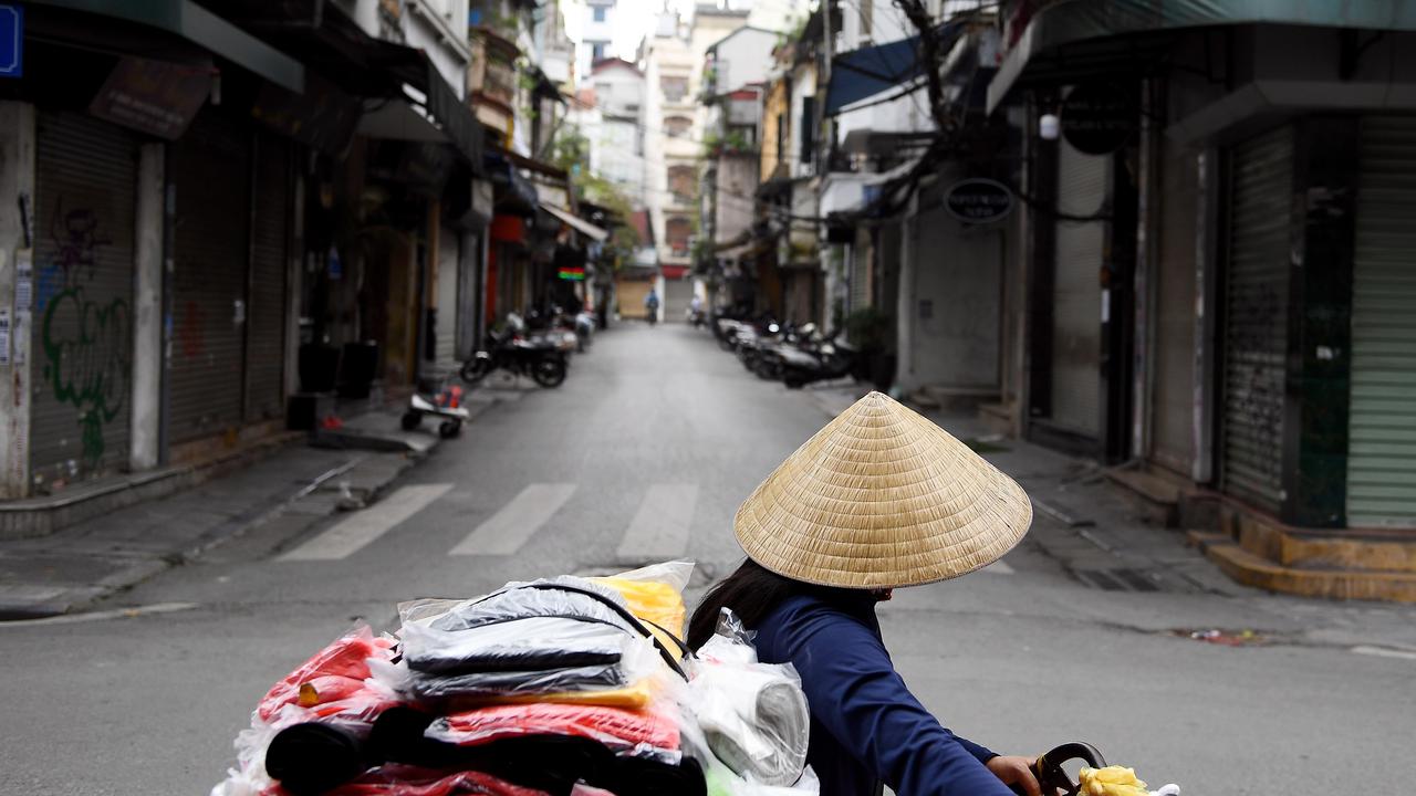 Seorang penjual berjalan melewati jalan sepi di tengah kekhawatiran tentang penyebaran Virus Corona COVID-19 di Hanoi Vietnam pada 26 Maret 2020. (Nhac Nguyen / AFP)