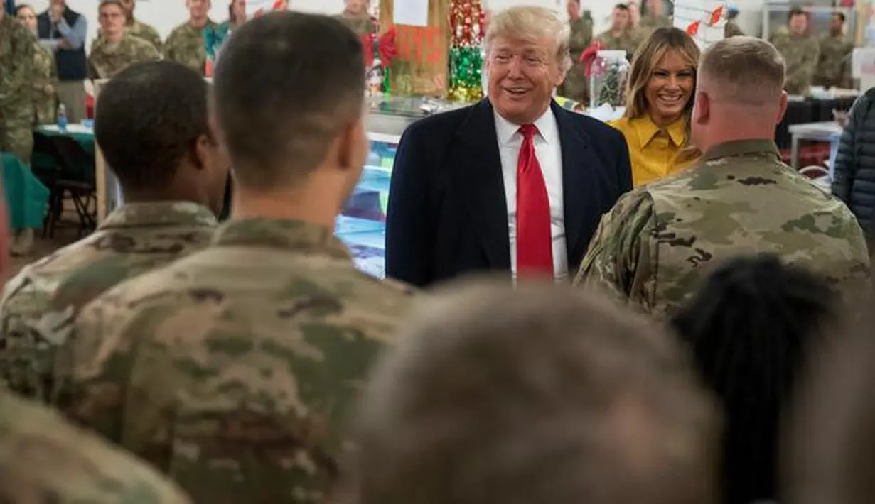 Presiden Donald Trump dan ibu negara Melania Trump mengunjungi pasukan militer Amerika di Pangkalan Udara al Asad, Irak, Rabu (26/12). Trump memberikan kejutan dengan melakukan kunjungan mendadak tersebut dalam rangka perayaan Natal. (AP/Andrew Harnik)