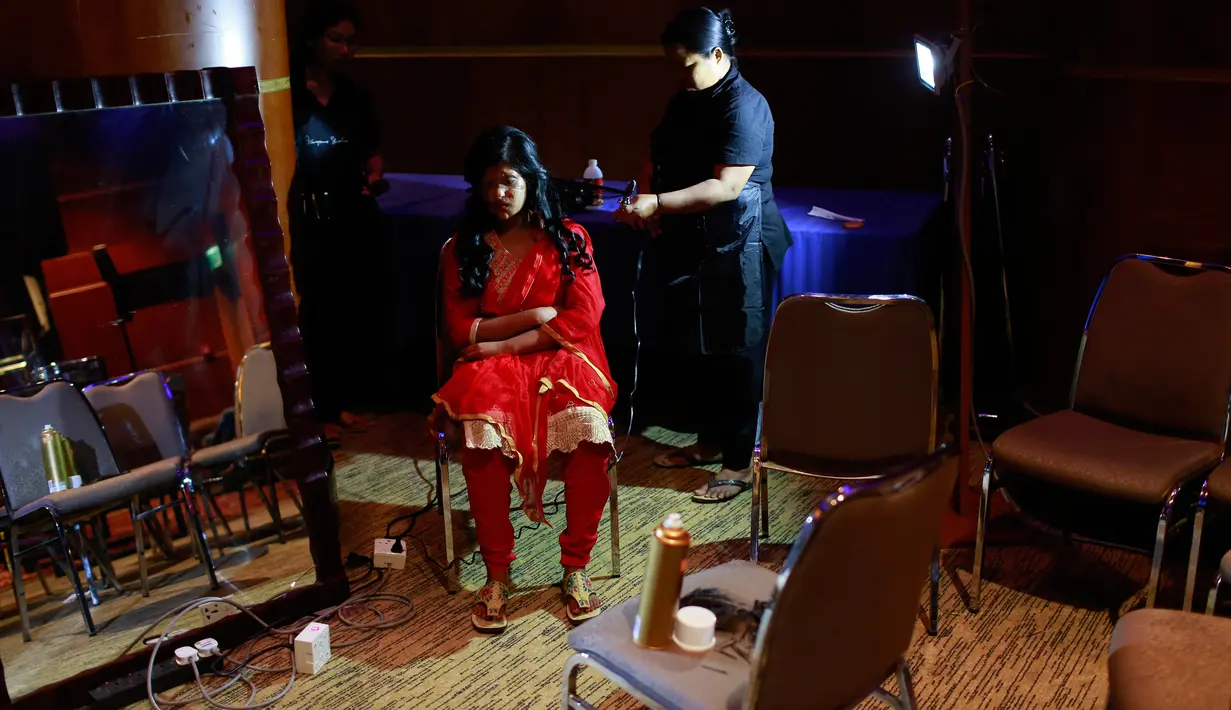 Penata rias menata rambut wanita korban serangan cairan asam sebelum tampil pada pagelaran busana "Beauty Redefined" di Dhaka, Bangladesh, 7 Maret 2017. Peragaan ini untuk menumbuhkan pemahaman warga terhadap kejahatan cairan asam. (AP Photo/A. M. Ahad)