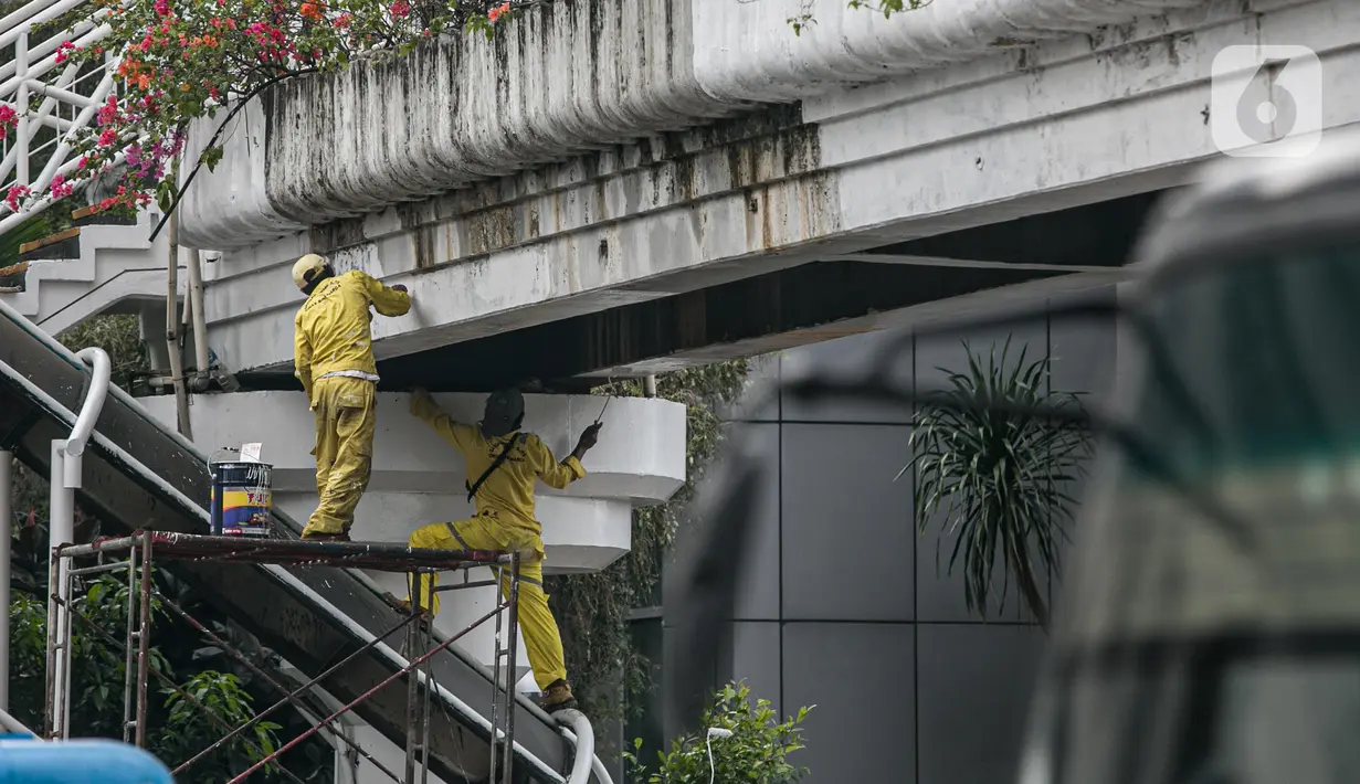 Sejumlah pekerja melakukan pengecatan ulang Penyeberangan Orang (JPO) di kawasan Thamrin, Jakarta, Kamis (28/1/2021). Pengecatan ulang tersebut dilakukan untuk merawat dan memelihara keberadaan fasilitas umum tersebut. (Liputan6.com/Faizal Fanani)