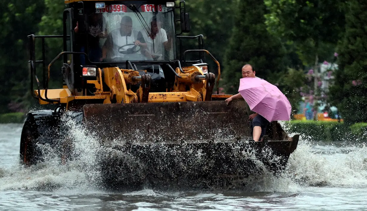  Sebuah ekskavator saat melewati banjir di Yuncheng, Provinsi Shanxi, China, (19/7). Curah hujan terberat yang mengguyur China selama beberapa hari terakhir telah mengakibatkan banjir merendam sejumlah daerah. (REUTERS/Stringer)