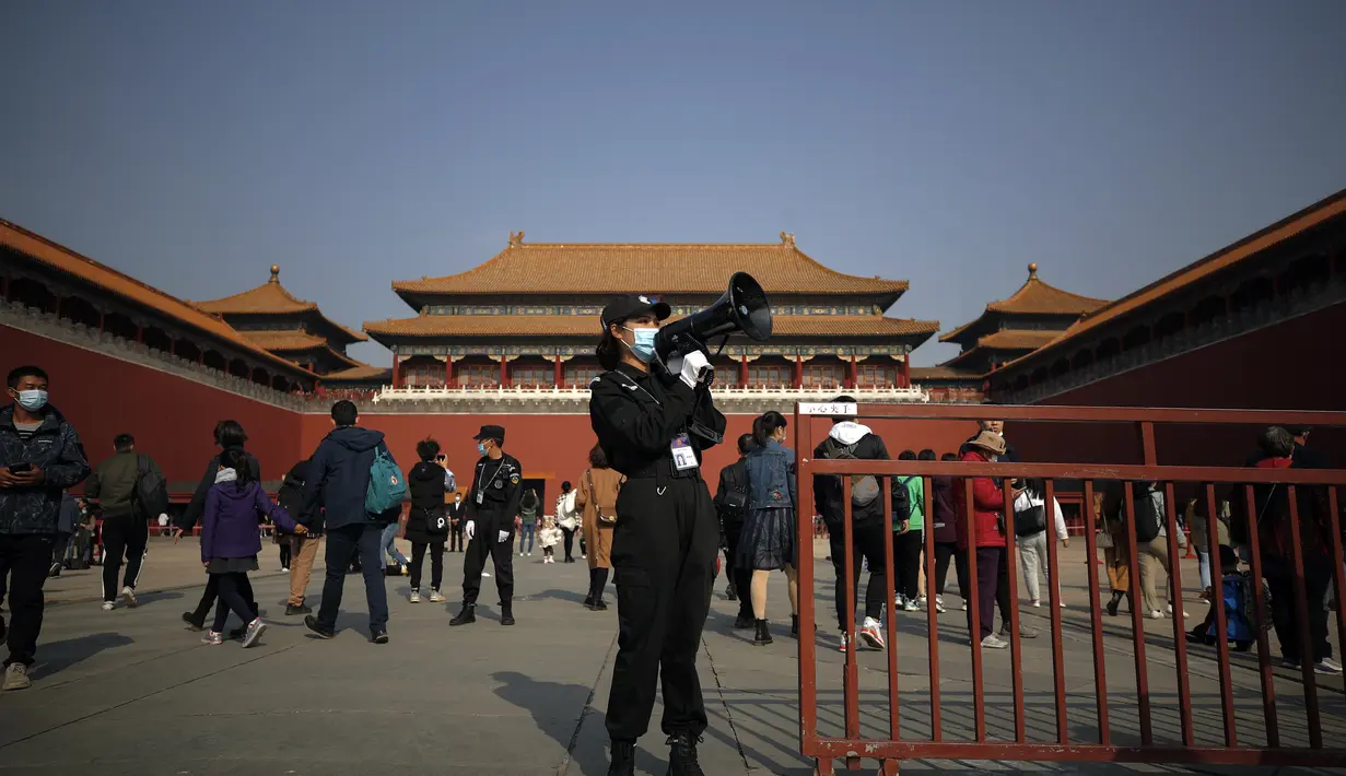 Seorang penjaga keamanan menggunakan pengeras suara untuk menyarankan wisatawan untuk memindai kode kesehatan mereka sebelum memasuki Kota Terlarang di Beijing (25/10/2020). (AP Photo/Andy Wong)