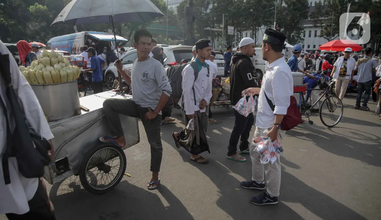 Pedagang jagung rebus menunggu pembeli saat berjualan di tengah aksi reuni 212, sekitaran Jalan Medan Merdeka Barat, Jakarta, Senin (2/12/2019). Sejumlah PKL meraup untung dengan berjualan di tengah ribuan massa Persaudaraan Alumni 212 yang mengikuti reuni di Monas. (Liputan6.com/Faizal Fanani)