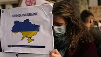 Seorang demonstran Pro-Ukraina memegang poster saat demonstrasi di luar Downing Street, di London, Kamis (24/2/2022). Demonstran turun ke jalan di London, Tokyo, Paris dan banyak kota lain untuk memprotes invasi Rusia ke Ukraina. (AP Photo/Alberto Pezzali)