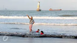 Sejumlah warga bermain air dipinggir Pantai Teluk Penyu Kabupaten Cilacap, Jawa Tengah,Jumat (29/7). Di Pantai Teluk Penyu pengunjung bisa memancing di tepian sambil menikmati terbenamnya matahari. (Liputan6.com/Helmi Afandi)