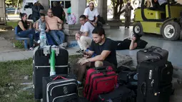 Seorang imigran Kuba memainkan ponselnya di luar gedung bea cukai di perbatasan antara Nikaragua dan Kosta Rika, Minggu (15/11). Nikaragua menutup perbatasannya dengan Kosta Rika hingga ribuan orang yang menuju Amerika terlantar. (REUTERS/Oswaldo Rivas)