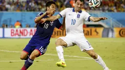 Gelandang Timnas Jepang, Shinji Kagawa (kiri), bertarung berebut bola dengan Giorgos Karagounis (Yunani) saat berlaga di babak penyisihan Piala Dunia 2014 Grup C di Stadion Dunas, Natal, Brasil, (20/6/2014). (REUTERS/Toru Hanai)