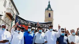 Warga saat menggelar aksi protes di kota pesisir Mediterania, Jaffa, Tel Aviv selatan (26/6/2020). Dalam aksinya mereka menolak situs pemakaman muslim tersebut dijadikan sebagai tempat penampungan tunawisma dan pembukaan ruang komersial baru. (AFP Photo/Jack Guez)