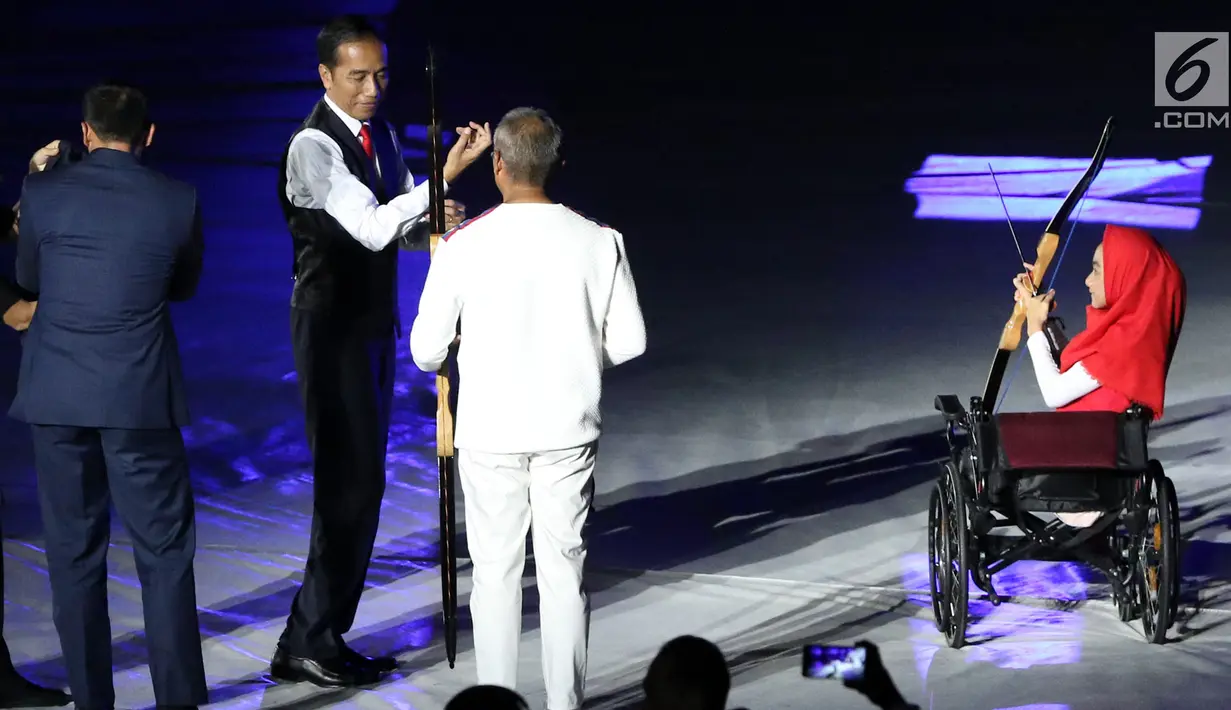 Presiden RI, Joko Widodo (tengah) bersiap memanah tugu bersama penyandang disabilitas saat malam pembukaan Asian Para Games 2018 di SUGBK, Jakarta, Sabtu (6/10).  Asian Para Games 2018 berlangsung 6-13 Oktober. (Liputan6.com/Helmi Fithriansyah)