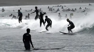 Orang-orang berselancar di pantai Katase-kaigan yang berangin, Fujisawa, Prefektur Kanagawa, selatan Tokyo, Jepang, Kamis (24/9/2020). Badai Tropis Dolphin bergerak di sepanjang pantai Pasifik Jepang. (AP Photo/Eugene Hoshiko)