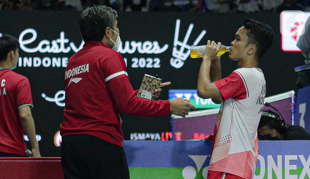 Pebulu tangkis tunggal putra Indonesia Anthony Sinisuka Ginting meminum air mineral saat jeda melawan Hans Kristian Solberg Vittinghus dari Denmark usai menang dalam babak 16 besar East Ventures Indonesia Open 2022 di Istora Senayan, Jakarta, Kamis (16/6/2022). Anthony Ginting berhasil melaju ke perempat final setelah menang 21-17, 21-9. (Liputan6.com/Faizal Fanani)