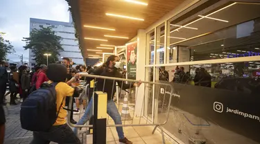 Demonstran mendobrak pintu masuk supermarket Carrefour selama protes terhadap pembunuhan pria kulit hitam Joao Alberto Silveira Freitas di Rio de Janeiro, Brasil (20/11/2020). Freitas meninggal setelah dipukuli oleh penjaga keamanan supermarket di kota Porto Alegre, Brasil selatan. (AP Photo/Bruna P