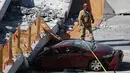 Sebuah mobil hancur akibat tertimpa jembatan pejalan kaki yang runtuh di Miami, Florida (15/3). Jembatan ini menghubungkan Universitas Internasional Florida dengan kos atau asrama mahasiswa. (Joe Raedle/Getty Images/AFP)