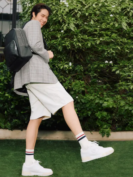 <p>Ia tampil dengan wade backpack hitam dipadukan blazer abu-abu dipadukan celana pendek putih dan sneakers putih dan kaos kaki. [dok. Coach]</p>