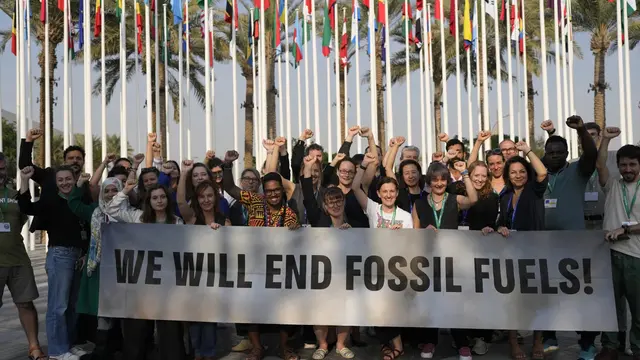 Anggota Greenpeace berkumpul sambil membawa spanduk seruan mengakhiri bahan bakar fosil di COP28 Rabu 13 Desember 2023 di Dubai UEA. (AP/Rafiq Maqbool)