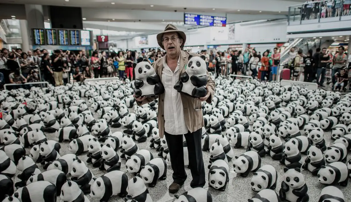 Seniman Prancis Paulo Grangeon berdiri di antara 1600 panda yang terbuat dari bubur kertas di Bandara Internasional Hong Kong, Senin (9/6/14). (AFP PHOTO/Philippe Lopez)