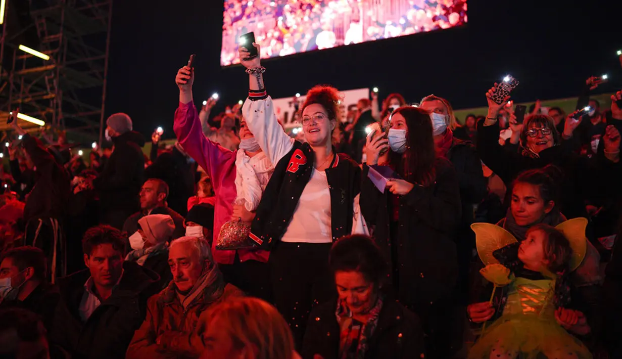 Para penonton karnaval melambaikan ponsel mereka ke udara saat upacara pembukaan Karnaval Nice di Nice, Prancis, 11 Februari 2022. Tema karnaval edisi ke-149 kali ini adalah Raja Hewan. (AP Photo/Daniel Cole)