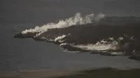 Lava dari gunung berapi Cumbre Vieja mengalir ke Samudra Atlantik terlihat dari Puerto de Naos, di Pulau Canary La Palma (4/10/2021). Aliran baru lava yang sangat cair muncul dari gunung berapi yang meletus di pulau Canary Spanyol pada 1 Oktober, kata pihak berwenang. (AFP/Jorge Guerrero)