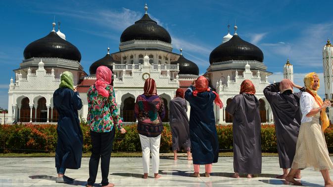 Turis asing dengan mengenakan kerudung mengambil gambar Masjid Agung Baiturrahman di Banda Aceh, Aceh pada 6 Agustus 2019. Selain sebagai tempat ibadah, Masjid Baiturahman juga menjadi tempat wisata bagi turis lokal dan mancanegara. (CHAIDEER MAHYUDDIN / AFP)