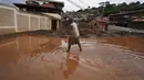 Seorang warga membersihkan lumpur dari jalan setelah banjir di Raposos, negara bagian Minas Gerais, Brasil, Selasa (11/1/2022). Tanah longsor akibat hujan deras telah menewaskan sedikitnya 12 orang dan pihak berwenang sedang memantau bendungan yang bisa jebol. (AP Photo/Eugenio Savio)
