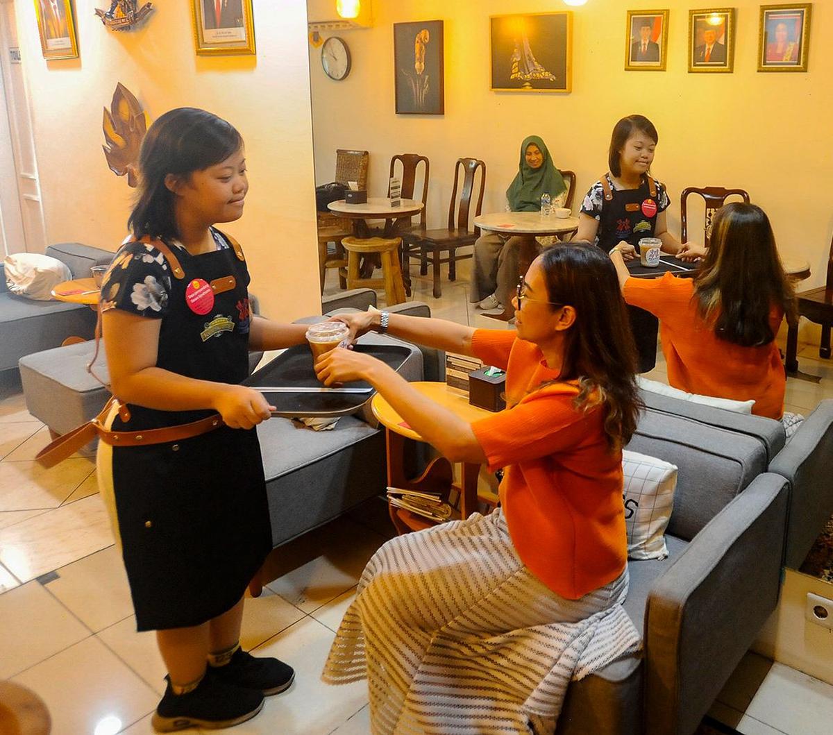 Penyandang down syndrome menyajikan kopi untuk pengunjung di Kopi Kamu, Kebayoran Baru, Jakarta Selatan, pada Selasa (5/12/2023). Coffee shop yang berada di bawah naungan Persatuan Orang Tua Anak Dengan Down Syndrome (POTADS) ini memberikan kesempatan bag