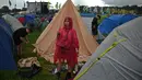 Para pengunjung tetap bergembira meskipun basah kuyup saat mendirikan tenda dan menikmati hari pertama perayaan di Worthy Farm di Somerset. (Photo by Oli SCARFF / AFP)