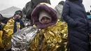 Anak-anak terbungkus selimut termal mencoba untuk tetap hangat setelah melarikan diri dari Ukraina dan tiba di perbatasan di Medyka, Polandia, Senin (7/3/2022). Hampir 2 juta orang telah melarikan diri sejak Rusia menginvasi Ukraina dengan jumlah itu meningkat setiap hari. (AP Photo/Visar Kryeziu)