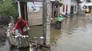 Aktivitas warga di depan rumahnya yang tergenang banjir rob di Desa Pantai Mekar, Muaragembong, Kabupaten Bekasi, Senin (6/12/2021). Banjir rob telah menggenangi rumah dan tambak warga di wilayah tersebut selama empat hari akibat kenaikan permukaan air laut. (Liputan6.com/Herman Zakharia)