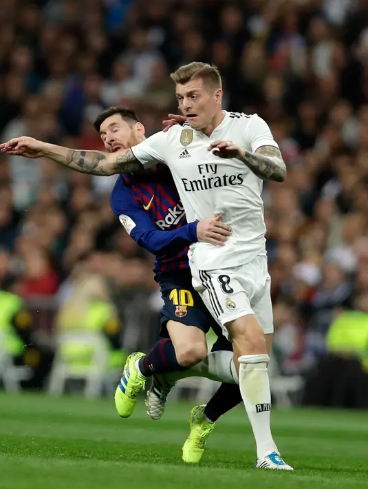 Pemain Real Madrid, Toni Kroos berebut bola dengan penyerang Barcelona, Lionel Messi pada laga leg kedua semifinal Copa del Rey di Stadion Santiago Bernabeu, Rabu (27/2). Barcelona merebut tiket final Copa del Rey usai menang 3-0. (AP/ Manu Fernandez)