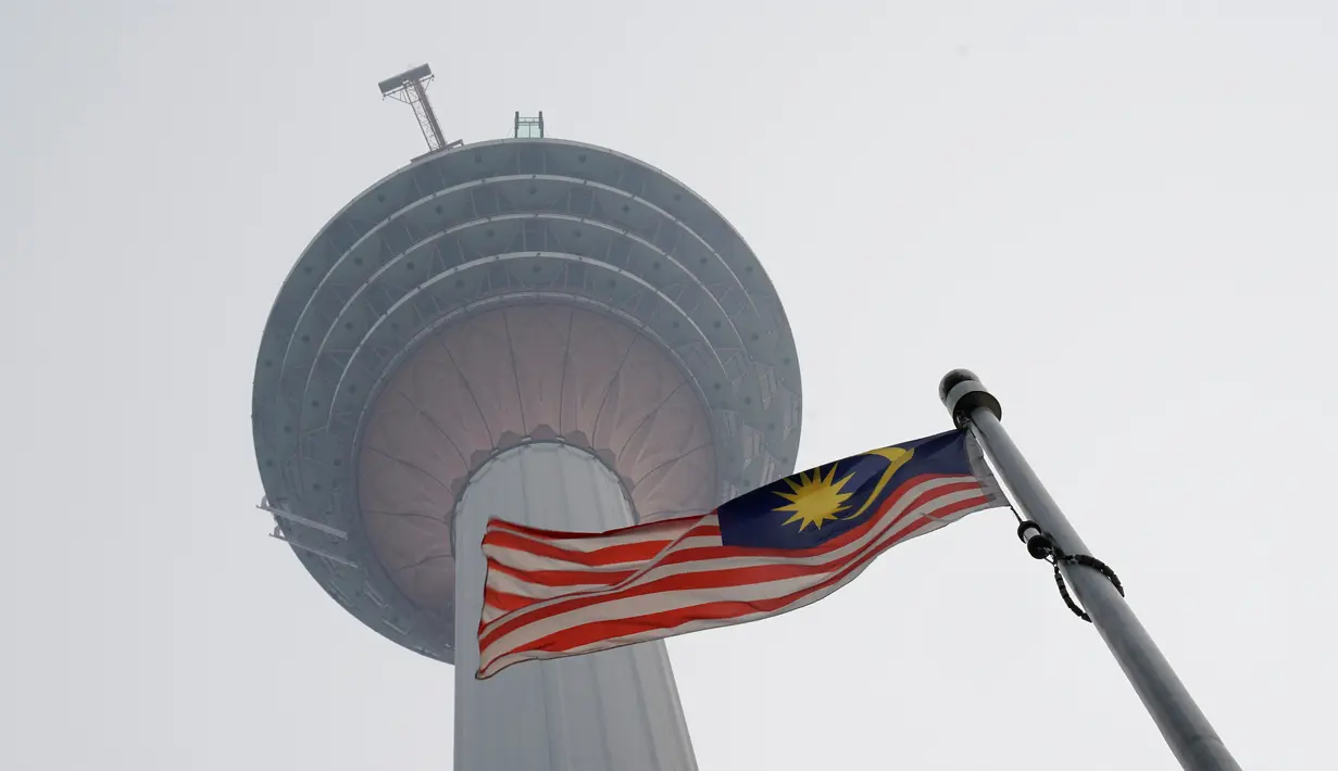 Bendera Malaysia berkibar di bawah Kuala Lumpur Tower saat kabut asap menyelimuti Kuala Lumpur, Malaysia, Rabu (18/9/2019). Badan Meteorologi Klimatologi dan Geofisika (BMKG) mendeteksi sebaran asap akibat kebakaran hutan dan lahan di Sumatra mencapai Malaysia dan Singapura. (AP Photo/Vincent Thian)