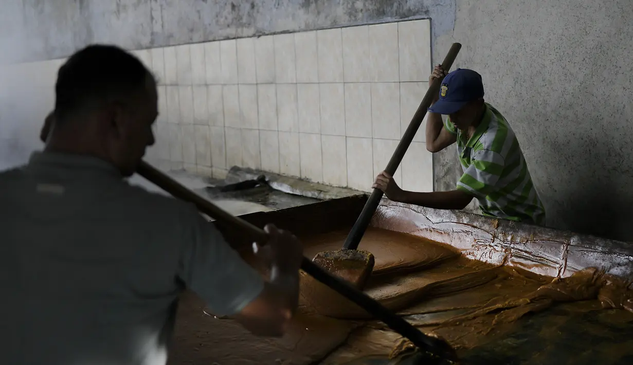 Seorang pekerja tebu memasak gula di trapiche panelero di Merida, Venezuela (21/9/2020). Jus tebu dibuat menjadi gula tebu utuh yang tidak dimurnikan yang dikenal sebagai panela, yaitu sukrosa berbentuk padat yang berasal dari perebusan dan penguapan sari tebu. (AP Photo/Matias Delacroix)