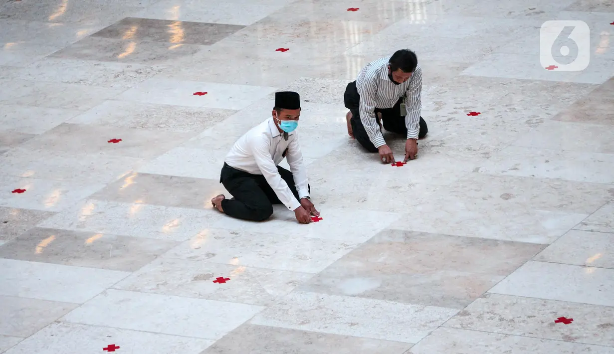 Petugas memasang tanda silang antar saf di Masjid Istiqlal, Jakarta Pusat, Selasa (2/6/2020). Masjid Istiqlal merupakan salah satu sarana ibadah yang dipersiapkan menerapkan prosedur standar new normal atau kenormalan baru. (Liputan6.com/Faizal Fanani)