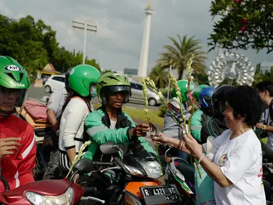 Gemabudhi membagikan bunga kepada pengguna jalan di depan Istana Negara, Jakarta, Sabtu (6/1). Aksi membagikan 2.561 tangkai bunga sedap malam tersebut dilakukan dalam rangka memperingati Hari Raya Trisuci Waisak 2561 B.E. (Liputan6.com/Immanuel Antonius)