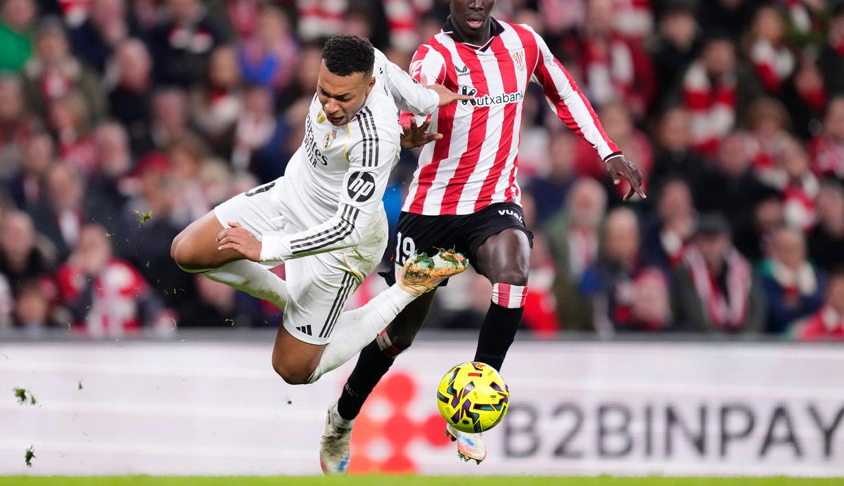 Pemain Real Madrid, Kylian Mbappe (kiri) berebut bola dengan pemain Athletic Bilbao, Adama Boiro dalam laga lanjutan Liga Spanyol 2025/2026 di Stadion San Mames, Bilbao, Spanyol, Rabu (03/12/2025). (AP Photo/Jose Breton)