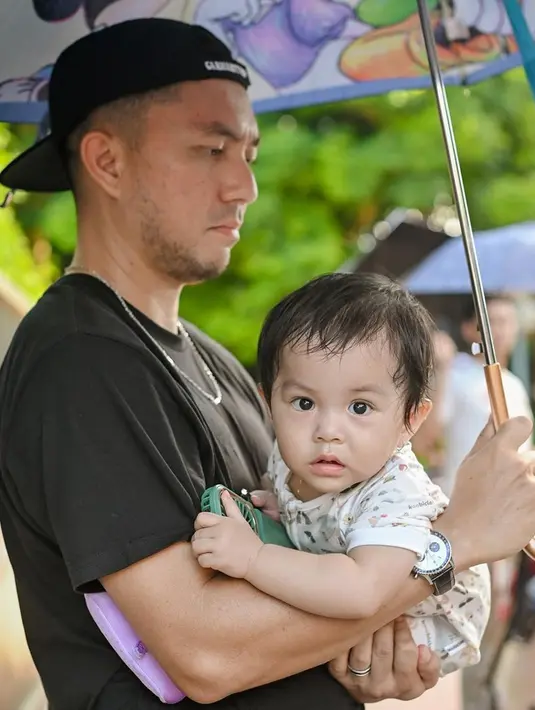 Tidak hanya romantis terhadap sang istri, Omesh juga berubah menjadi hot daddy yang siap siaga menjaga buah hati. Ia tampak momong anak bungsunya sambil memegang payung agar tidak kepanasan. Selama berada di Disneyland, para anggota Podkesmas memang memperlihatkan sisi kebapakan yang jarang ditampilkan di layar kaca. (Liputan6.com/IG/@podkesmas)