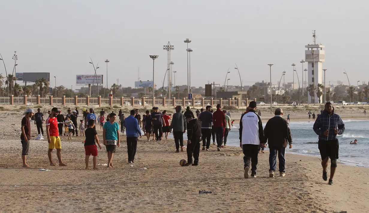 Orang-orang berolahraga di pantai sembari menunggu waktu berbuka puasa selama bulan suci Ramadan, meskipun lockdown karena pandemi COVID-19, di ibu kota Tripoli, Libya pada Jumat (8/5/2020). (Photo by Mahmud TURKIA / AFP)