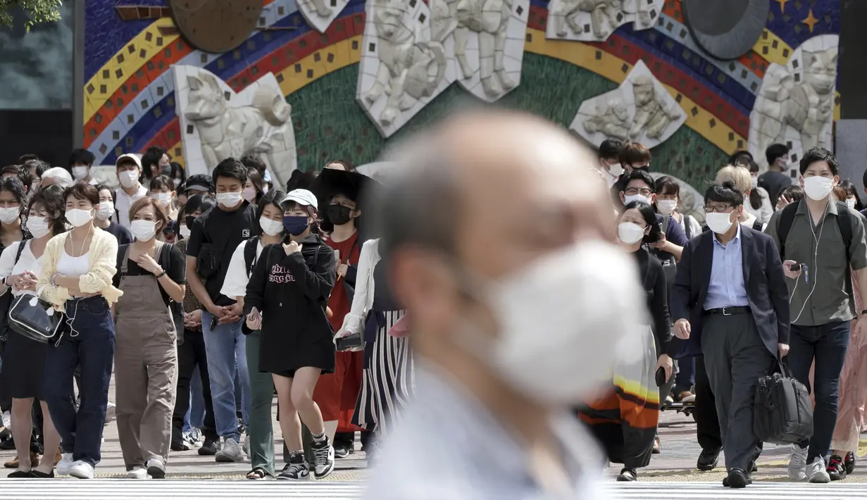 Orang-orang yang memakai masker menunggu untuk berjalan di sepanjang penyeberangan pejalan kaki di distrik Shibuya, Tokyo, Kamis (30/9/2021). Jepang akan mencabut keadaan darurat Covid-19 mulai Kamis ini karena jumlah kasus baru turun dan tekanan pada sistem medis mereda. (AP Photo/Eugene Hoshiko)