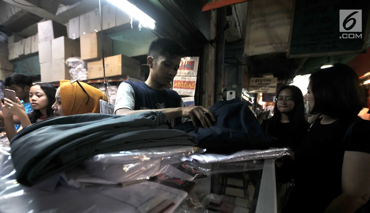 Calon pembeli sibuk memilih seragam sekolah di salah satu toko di Pasar Sunan Giri, Jakarta, Selasa (3/7). Orangtua murid mulai berburu seragam sekolah untuk anak mereka jelang tahun ajaran baru 2018/2019. (Merdeka.com/Iqbal Nugroho)
