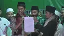 Mendapat todongan tersebut, Jokowi yang berada di panggung langsung menandatanganinya.  Jokowi memperlihatkan surat pernytaan kesediaannya, Malang, Jumat (27/6/2014) (Liputan6.com/Herman Zakharia)