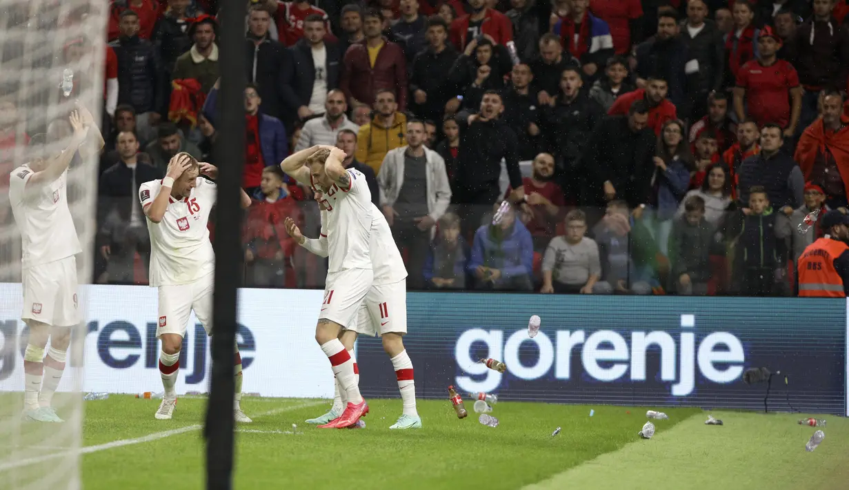 Para pemain Polandia menutupi kepala mereka saat suporter melemparkan botol tak lama setelah mencetak gol ke gawang Albania pada lanjutan Grup I Kualifikasi Piala Dunia 2022 Zona Eropa, di Air Albania Stadium, Rabu (13/10/2021) dini hari WIB. Polandia mengalahkan Albania 1-0. (AP Photo/Franc Zhurda)